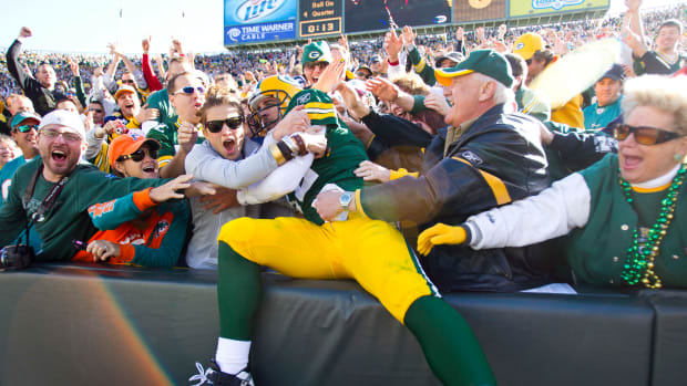 Green Bay Packers quarterback Aaron Rodgers leaps into the stands to celebrate a touchdown.