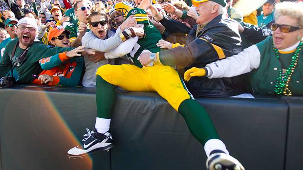 Green Bay Packers quarterback Aaron Rodgers leaps into the stands to celebrate a touchdown.