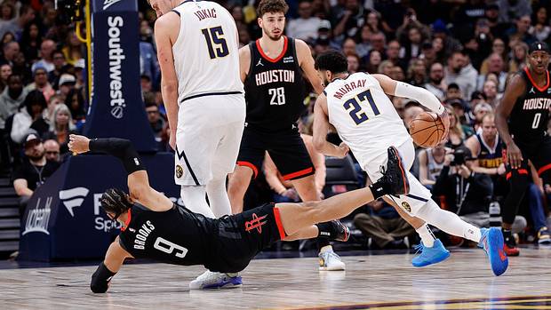 Rockets forward Dillon Brooks falls to the court after colliding with Nuggets center Nikola Jokic as he screens for guard Jamal Murray.