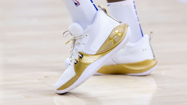View of white and gold Under Armour shoes.