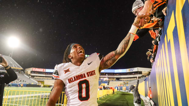 Oct 21, 2023; Morgantown, West Virginia, USA; Oklahoma State Cowboys running back Ollie Gordon II (0) celebrates with fans after defeating the West Virginia Mountaineers at Mountaineer Field at Milan Puskar Stadium. Mandatory Credit: Ben Queen-USA TODAY Sports
