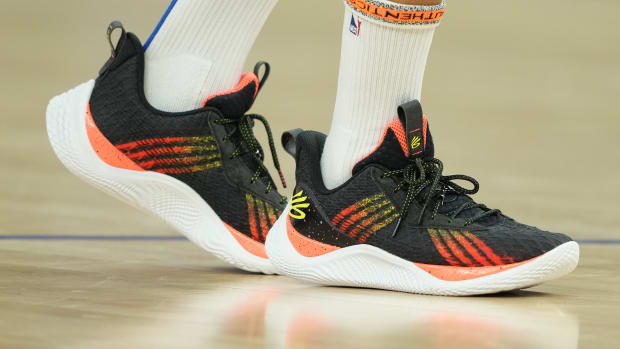 View of black, orange, and white Curry shoes.