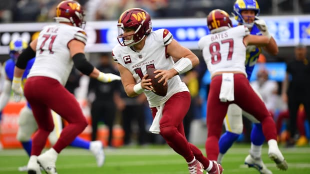 Washington Commanders quarterback Sam Howell (14) moves out to pass against the Los Angeles Rams during the first half at SoFi Stadium.