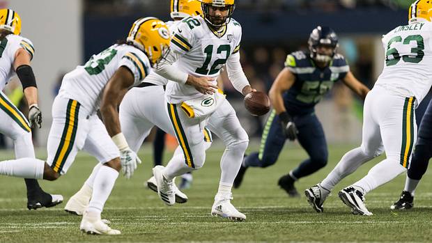 Green Bay Packers quarterback Aaron Rodgers hands the ball off to running back Aaron Jones.