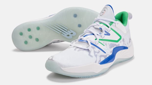 Side view of white, blue, and green New Balance shoes.