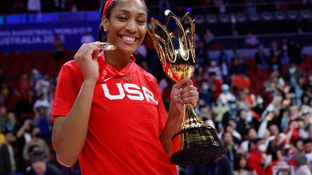 A'Ja Wilson holds up a gold medal and trophy.
