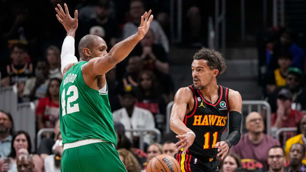 Atlanta Hawks guard Trae Young passes behind Boston Celtics center Al Horford.