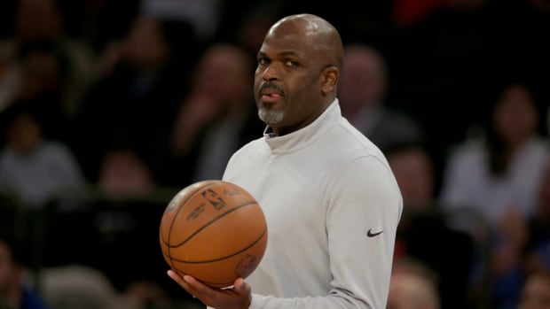 Nate McMillan holds a basketball on the sidelines.