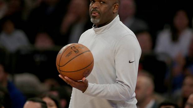 Nate McMillan holds a basketball on the sidelines.