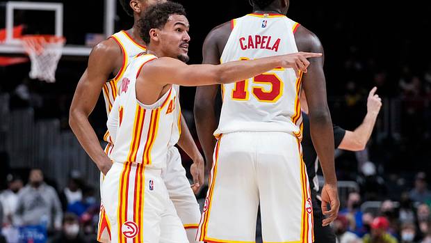 Trae Young stands beside De'Andre Hunter and Clint Capela.