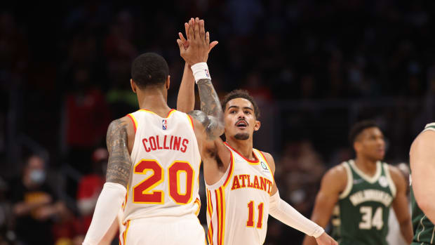 Trae Young and John Collins high-five each other.