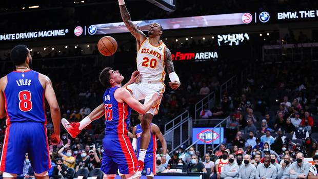 John Collins dunks over Detroit Pistons defnders.