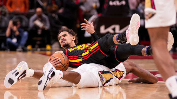 Trae Young reacts after ending up on top of Pelicans forward Naji Marshall.