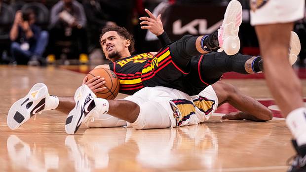 Trae Young reacts after ending up on top of Pelicans forward Naji Marshall.