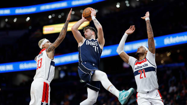 Dallas Mavericks star Luka Doncic throws a pass while being double-teamed by Washington Wizards' Kyle Kuzma and Daniel Gafford.