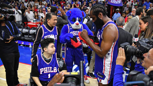 Philadelphia 76ers guard James Harden signs his shoes for a fan after a game.