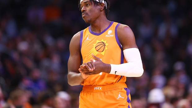 Aaron Holiday standing in Phoenix Suns uniform.