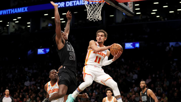 Hawks guard Trae Young passes the ball around Brooklyn Nets center Day'Ron Sharpe.