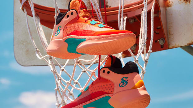 Orange Skechers basketball sneakers hang from an outdoor hoop.