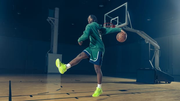 Tyrese Maxey models green New Balance apparel on a basketball court.