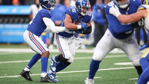 New York Giants quarterback Tyrod Taylor hands the ball off to running back Saquon Barkley.