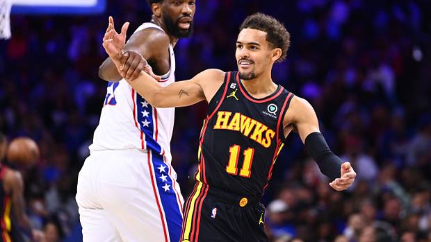 Hawks guard Trae Young reacts as 76ers center Joel Embiid grabs him.