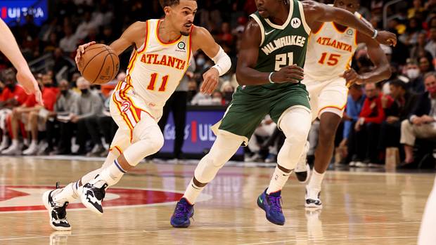 Trae Young drives past Bucks guard Jrue Holiday.
