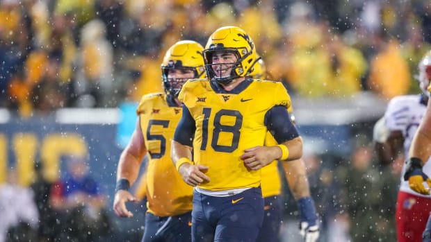 West Virginia Mountaineers quarterback JT Daniels (18) celebrates with teammates after throwing a touchdown pass during the fourth quarter against the Kansas Jayhawks at Mountaineer Field