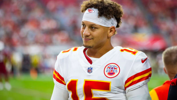 Chiefs quarterback Patrick Mahomes smiles on the sidelines of a game.