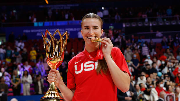 Sabrina Ionescu poses with a gold medal and trophy.