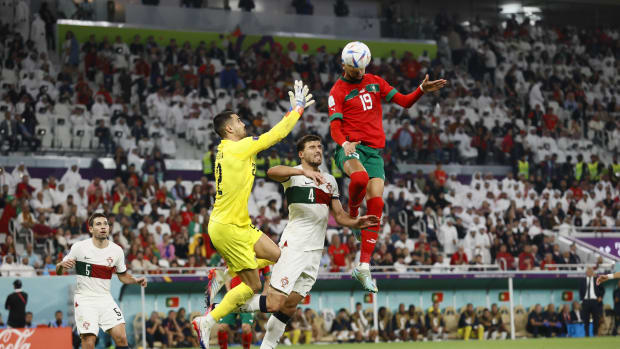 Morocco no.19 Youssef En Nesyri pictured outjumping Portugal goalkeeper Diogo Costa and defender Ruben Dias to score in a World Cup quarter-final at Qatar 2022