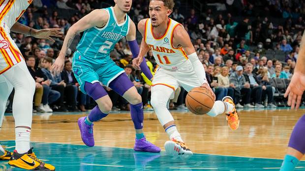 Hawks guard Trae Young dribbles past Hornets guard LaMelo Ball.