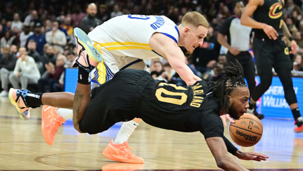Jan 20, 2023; Cleveland, Ohio, USA; Cleveland Cavaliers guard Darius Garland (10) is tripped up by Golden State Warriors guard Donte DiVincenzo (0) during the second half at Rocket Mortgage FieldHouse. Mandatory Credit: Ken Blaze-USA TODAY Sports
