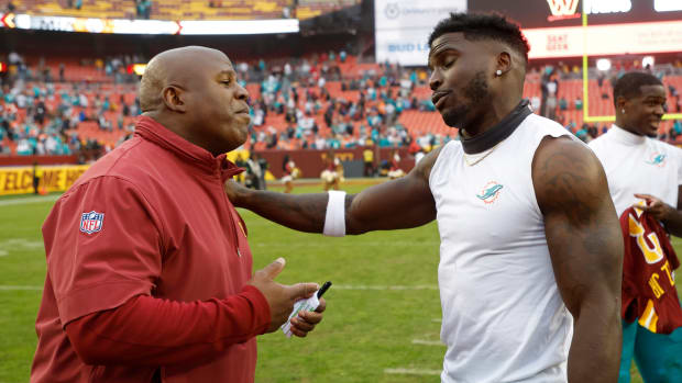 Miami Dolphins wide receiver Tyreek Hill (R) hugs Washington Commanders assistant head coach/offensive coordinator Eric Bieniemy (L) at FedExField.