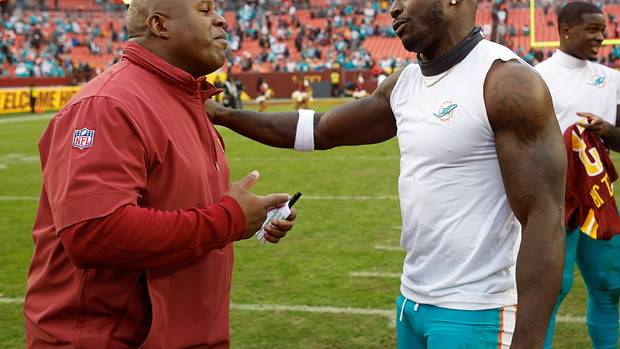 Miami Dolphins wide receiver Tyreek Hill (R) hugs Washington Commanders assistant head coach/offensive coordinator Eric Bieniemy (L) at FedExField.