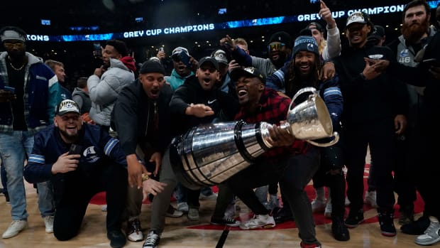 Nov 23, 2022; Toronto, Ontario, CAN; Toronto Argonauts linebacker Henoc Muamba (plaid shirt) and running back Andrew Harris (Nike hoodie) and teammates celebrate with the Grey Cup on the court during a break in the action between the Brooklyn Nets and Toronto Raptors the first quarter at Scotiabank Arena. Mandatory Credit: John E. Sokolowski-USA TODAY Sports  