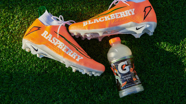 Shedeur Sanders orange and white Nike cleats next to a Gatorade bottle.
