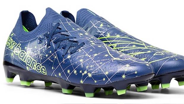 Side view of blue and green New Balance soccer cleats.