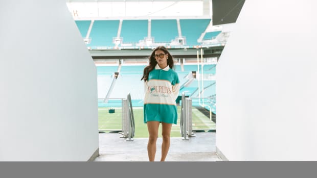 A woman models Miami Dolphins apparel in a football stadium.