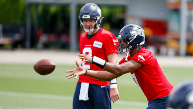 Seattle Seahawks quarterback Geno Smith (7) receives a shotgun snap in front of quarterback Drew Lock (2) during minicamp practice at the Virginia Mason Athletic Center Field.