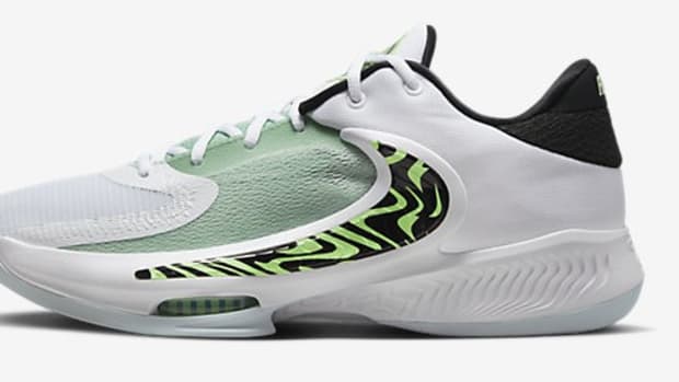 Side view of a green and white Nike basketball shoe.