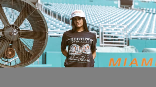 A woman models Miami Dolphins apparel on a football field.