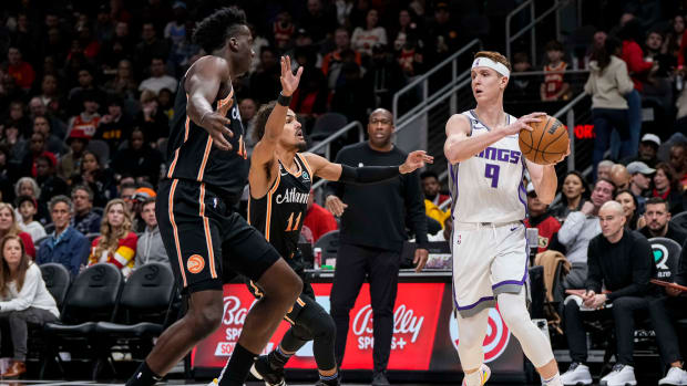 Kings guard Kevin Huerter passes the ball over Hawks center Clint Capela and guard Trae Young.