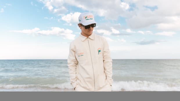 A man models Miami Dolphins apparel on a beach.