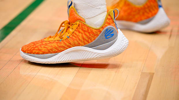 View of orange and white Curry shoes.