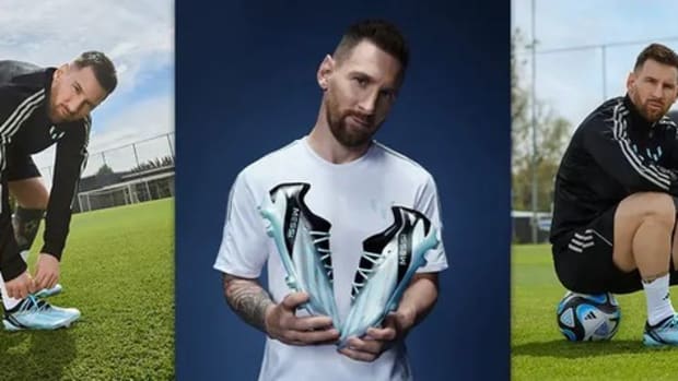 Lionel Messi models blue and black adidas soccer shoes.