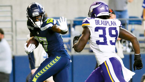 Former Arkansas Razorback wide receiver Matt Landers holds out his arm against Minnesota Vikings linebacker Abraham Beauplan  before scoring a game-clinching touchdown for the Seattle Seahawks during the second half at Lumen Field.