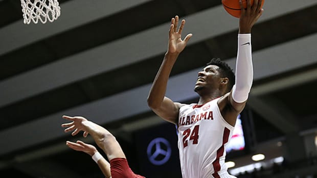 Brandon Miller plows over Anthony Black during an 86-83 win by Alabama over Arkansas.