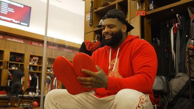 Trent Williams holds red sneakers in the San Francisco 49ers locker room.