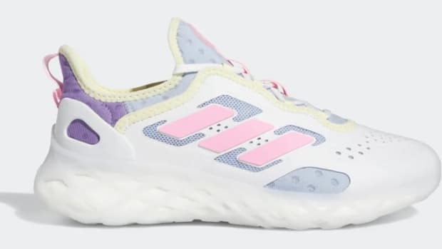 Side view of a white and pink adidas shoe.